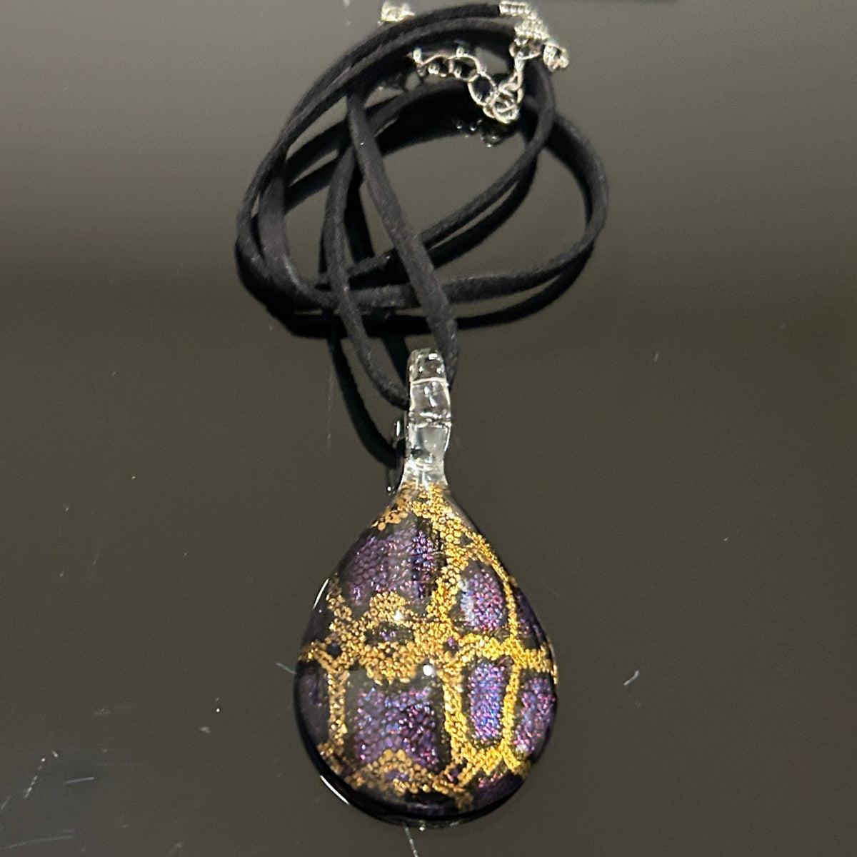 Handmade tree of life pendant in dichroic glass. 2 inches long, 1.25 inches wide. Blue and gold geometric design. Solid glass construction. 21" cloth cord included.